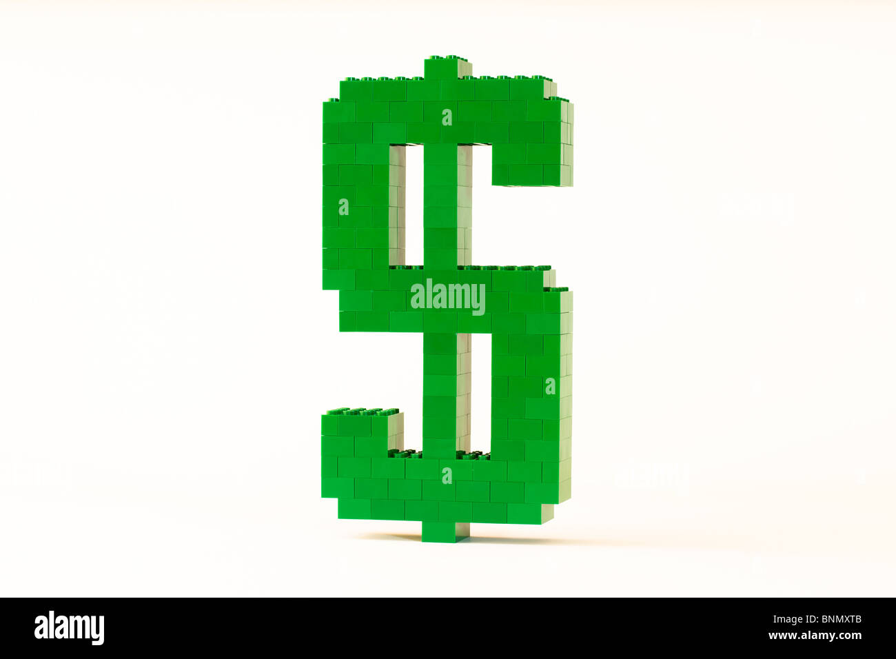 Ein grünes Dollarsymbol aus Spielzeug Ziegel gebaut und erschossen vor einem weißen Hintergrund in einem Winkel zu zeigen, dass es 3D Natur ist. Stockfoto