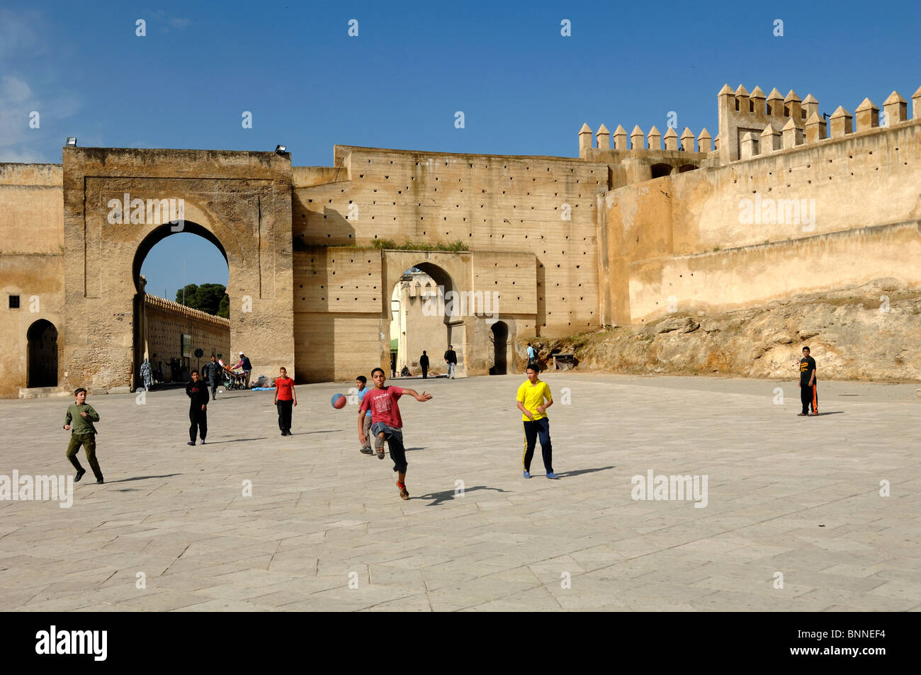 Marokkanische Jungen spielen Fußball auf dem Bou Jeloud Stadtplatz unter der Stadt oder Stadtmauer, Fez, Marokko Stockfoto