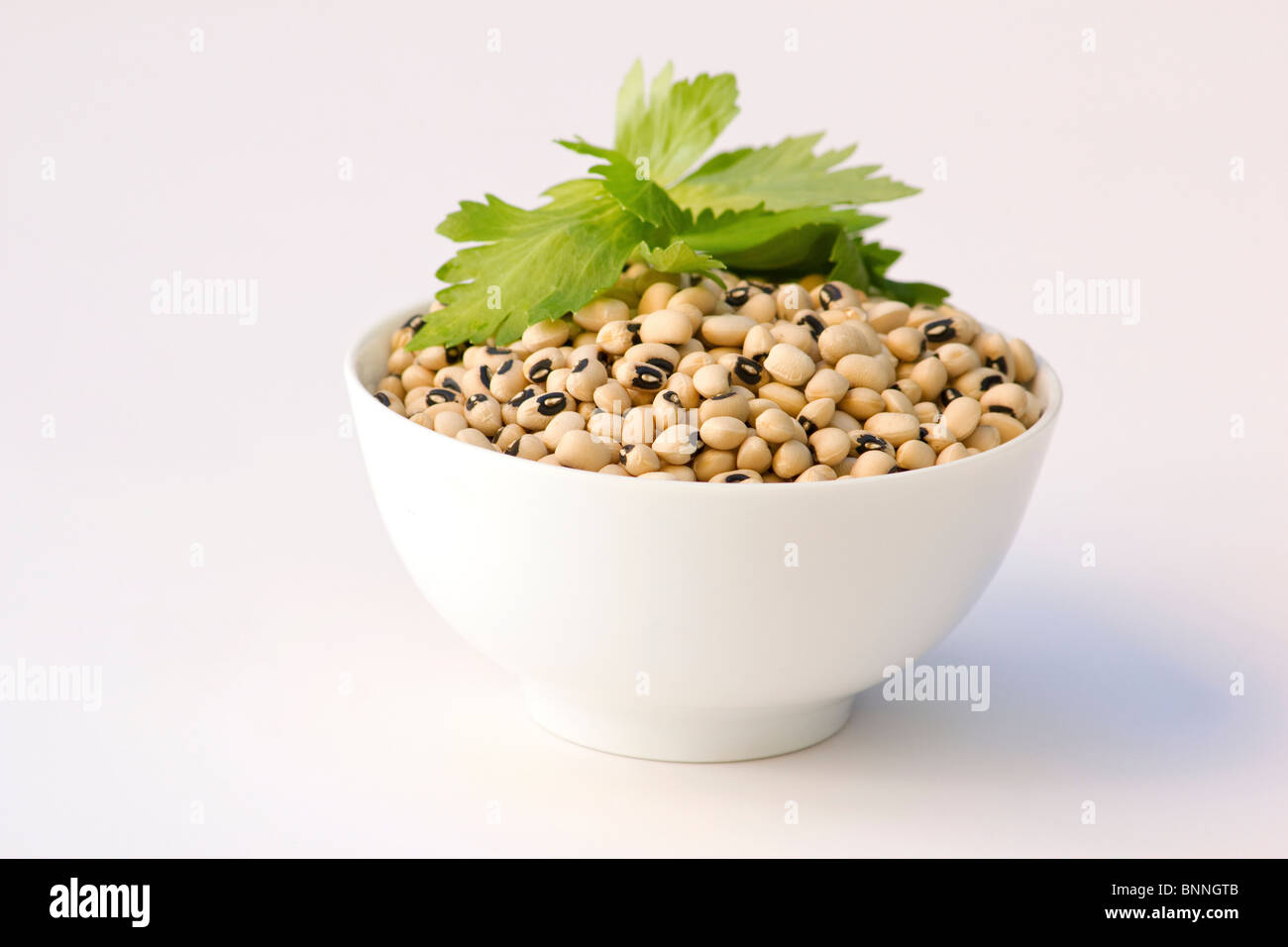 Black-eyed Peas in einer weißen Schüssel mit Kraut lässt Stockfoto