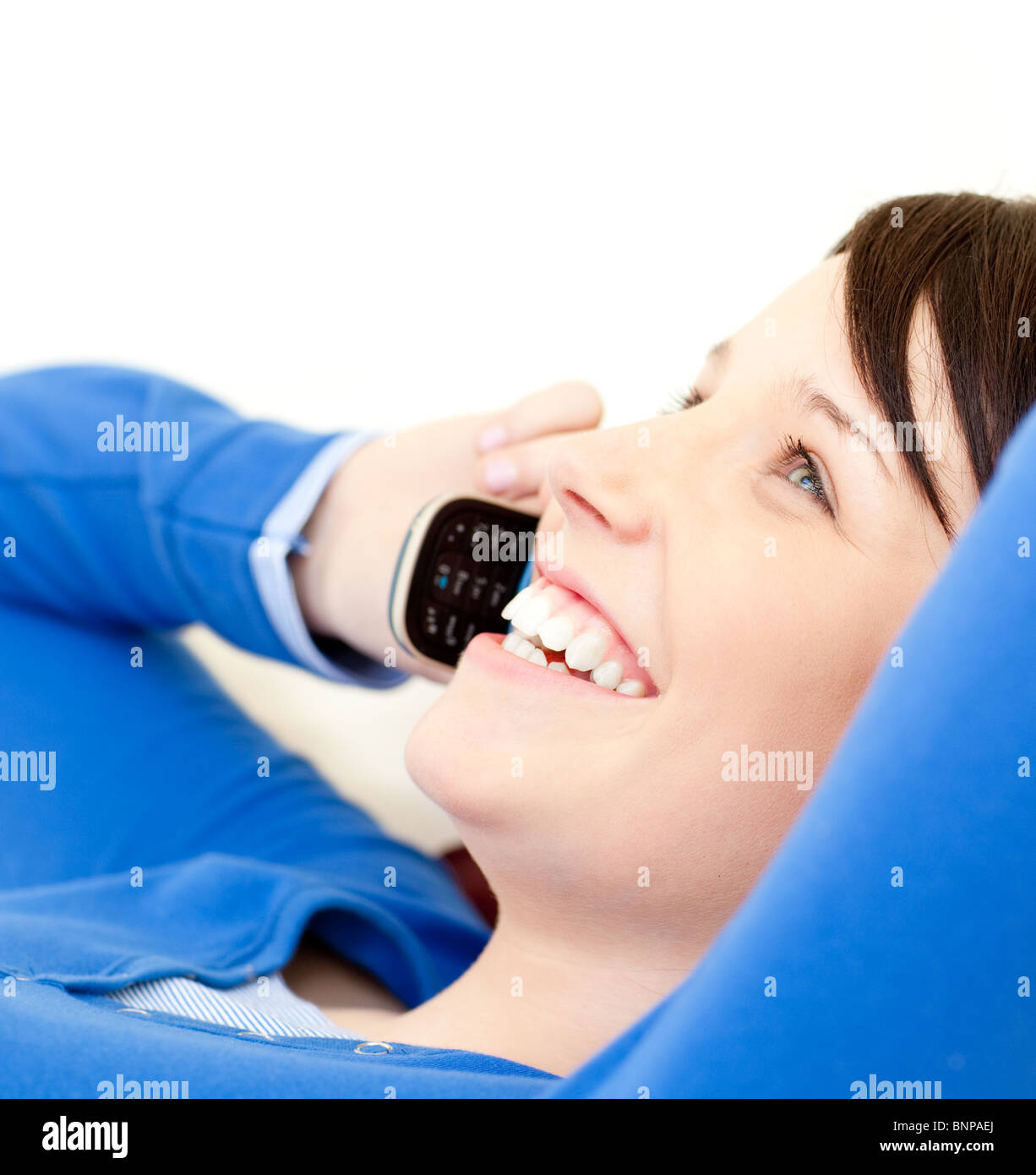 Lustiger junge Frau am Telefon auf einem Sofa liegend Stockfoto