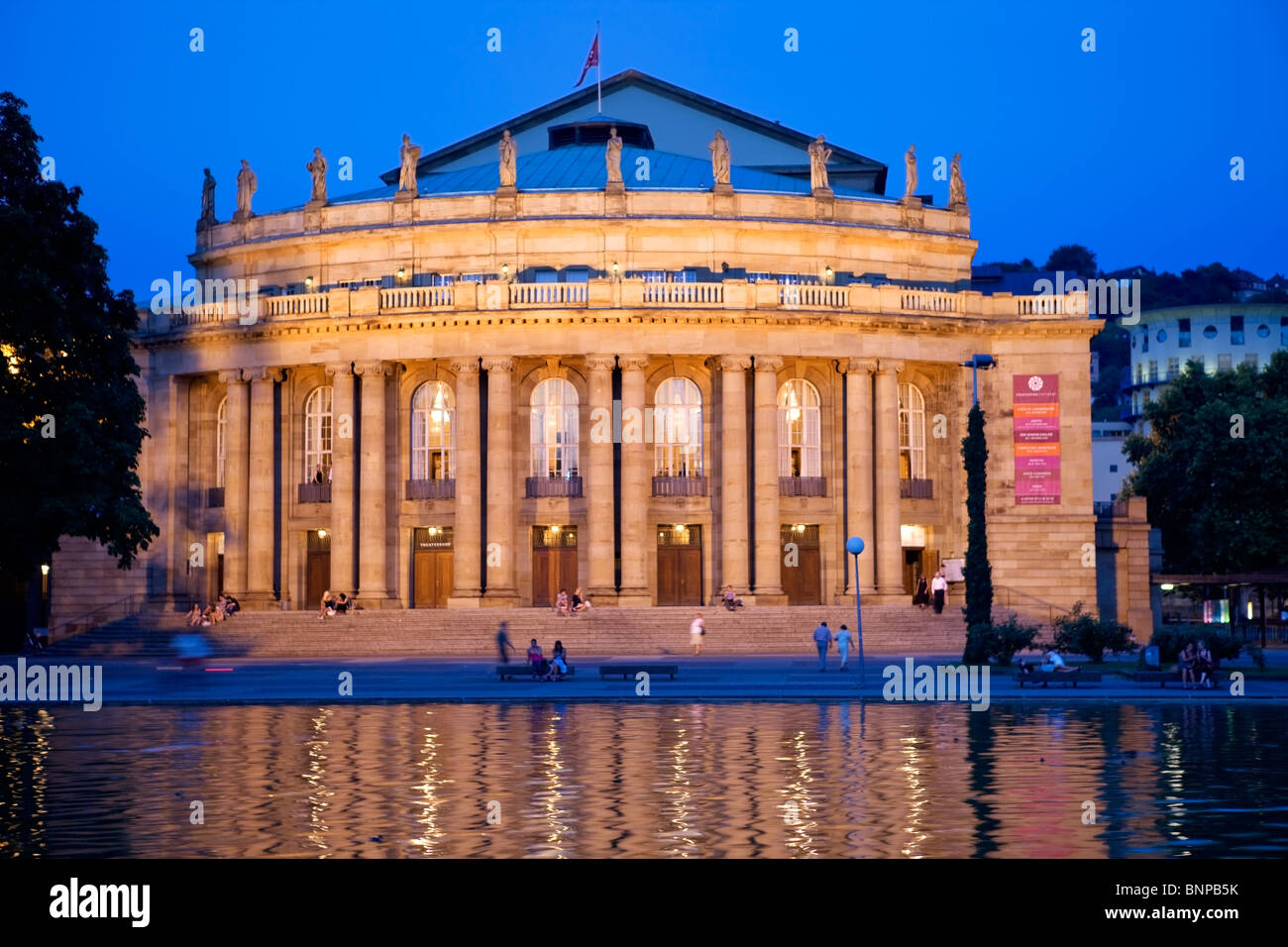 Nachtaufnahme von der beleuchteten Opernhaus in Stuttgart, Deutschland, See Theatersee im Vordergrund, Passanten, Begleiter Stockfoto