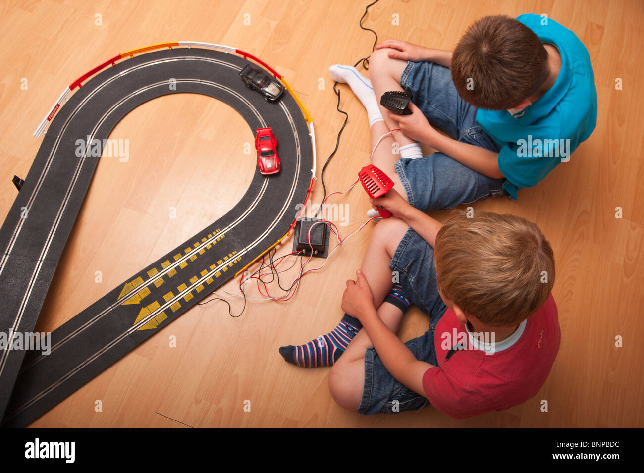 Ein MODEL Release Bild von zwei jungen setzen (6 & 10) spielen mit einem Hornby Scalextric Rennwagen Spiel im Vereinigten Königreich Stockfoto