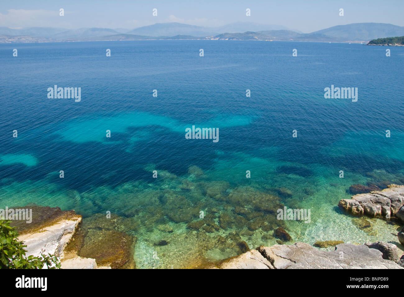 Felsküste bei Kassiopi auf der griechischen Mittelmeer Insel von Corfu Griechenland GR mit albanischen Berge am Horizont Stockfoto