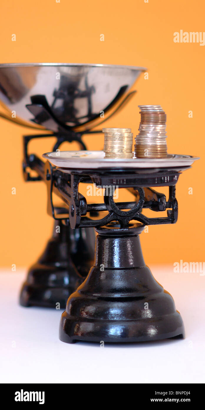 Eine Reihe von schwarzen Schuppen mit Münzen wie die Gewichte UK Stockfoto