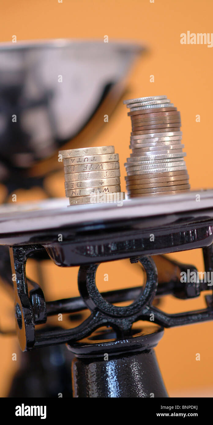 Eine Reihe von schwarzen Schuppen mit Münzen wie die Gewichte UK Stockfoto