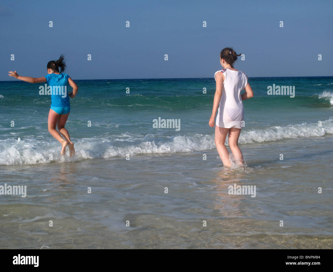 Zwei Mädchen spielen in Wellen am Strand Stockfoto
