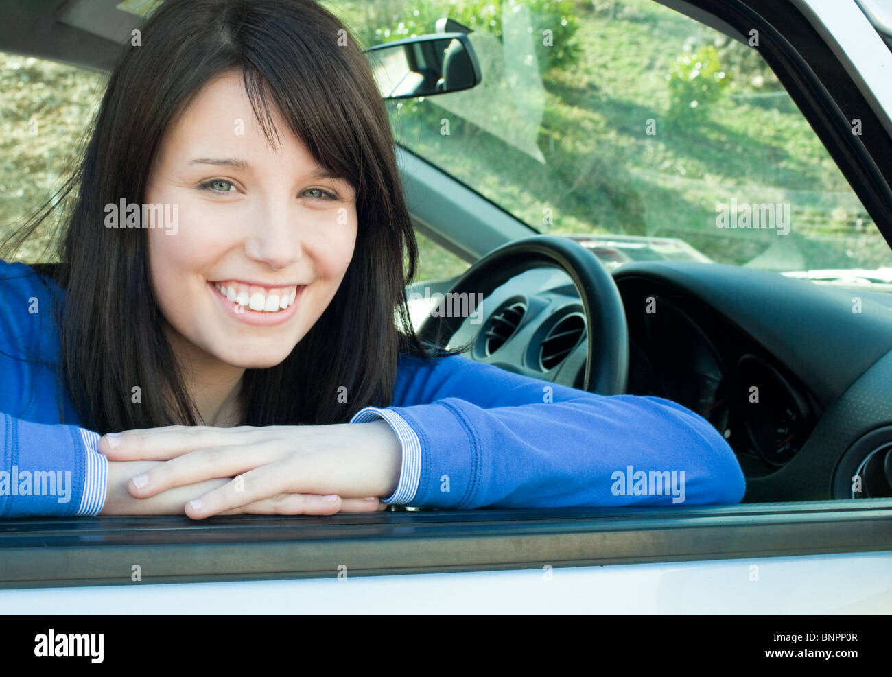Glücklich lächelnd in die Kamera sitzt in ihrem Auto Teengirl Stockfoto
