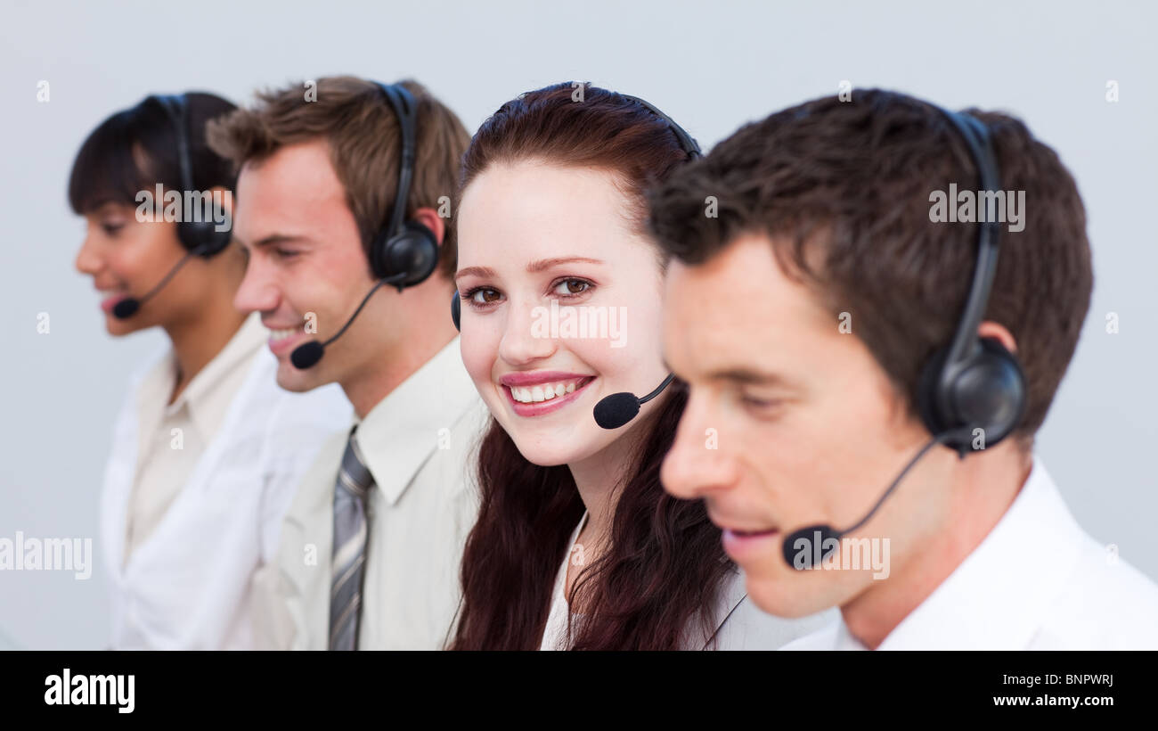 Lächelnde Frau arbeitet in einem Call-Center mit ihren Kollegen Stockfoto