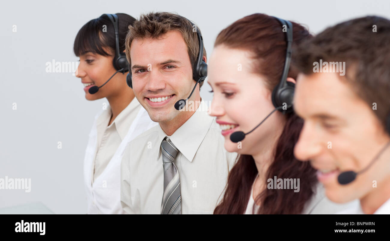 Lächelnder Mann arbeitet in einem Call-Center mit seinen Kollegen Stockfoto