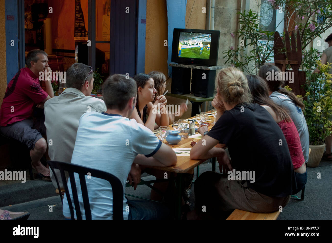 Arles, Frankreich, Leute auf der Terrasse des Bistro-Restaurants der französischen Provinz, Drinks teilen, Fußballspiele bei T.V.group Freunden in der Ferienstadt [Rear] anschauen, die raucht Stockfoto