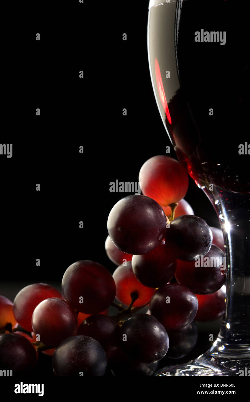 Nahaufnahme von roten Trauben und einem Glas Rotwein Stockfoto