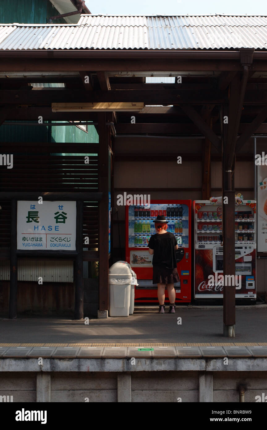 Eine junge Frau mit orangen Haaren kauft ein kaltes Getränk aus dem Automaten an Hase in Kamakura, Japan. August 2008. Stockfoto