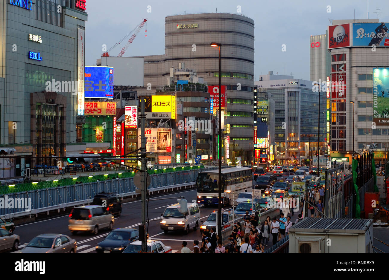 Verkehr und Menschenmassen in der Abenddämmerung außerhalb Bahnhof Shinjuku in Tokio, Japan. Stockfoto