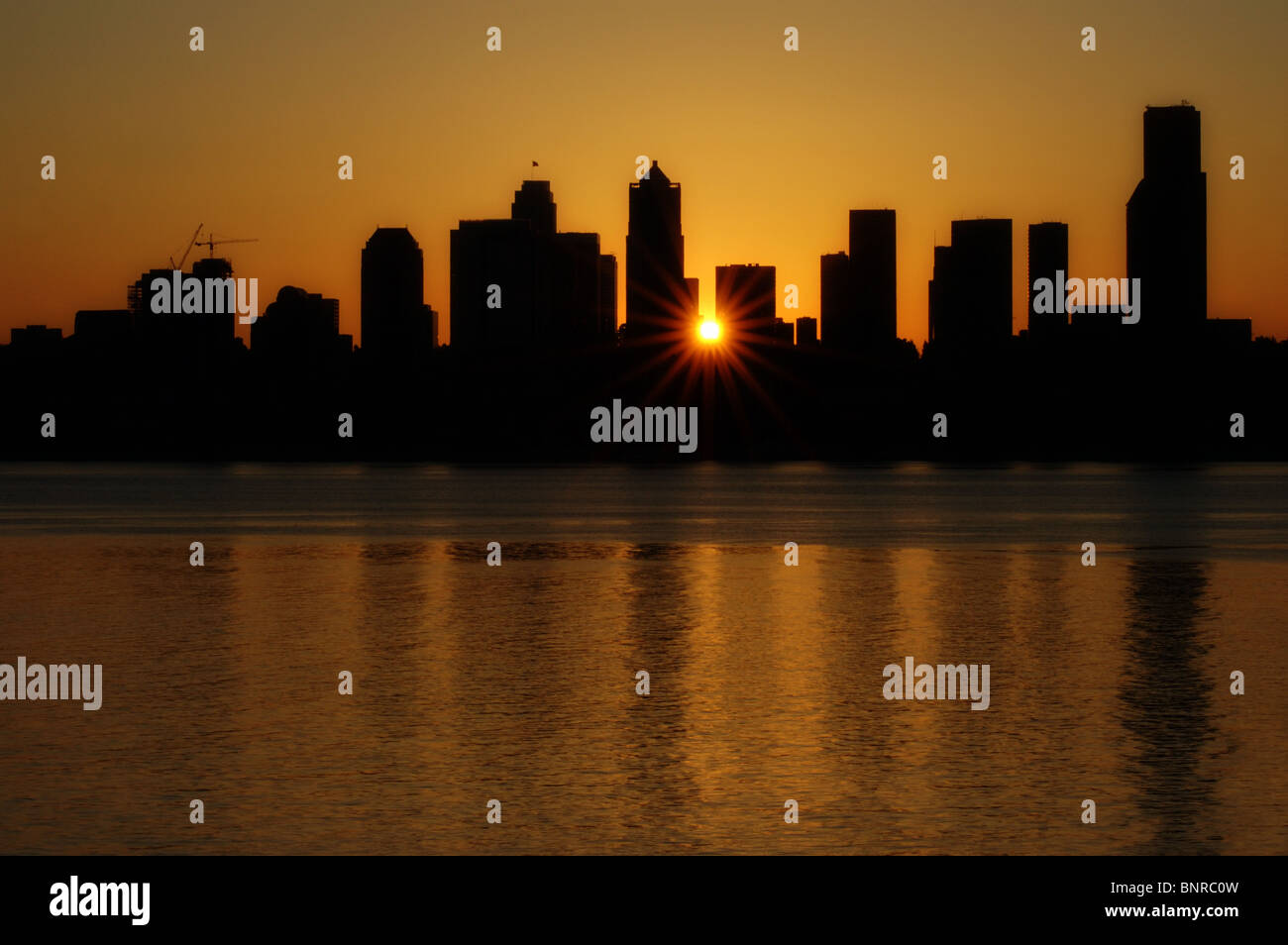 Atemberaubende orange Sonnenaufgang über der Innenstadt von Seattle, WA Skyline mit allen Gebäuden in Silhouette, Juni 2008. Stockfoto