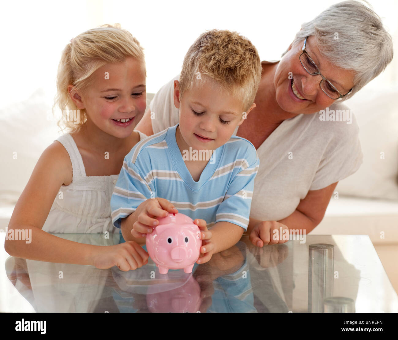 Großmutter und Kindern Geld zu sparen in ein Sparschwein Stockfoto