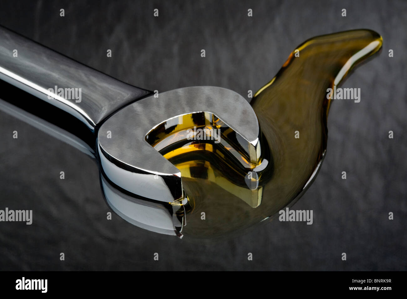 Ein Metall Schraubenschlüssel liegen in einem Pool von Öl Schmierstoff Stockfoto