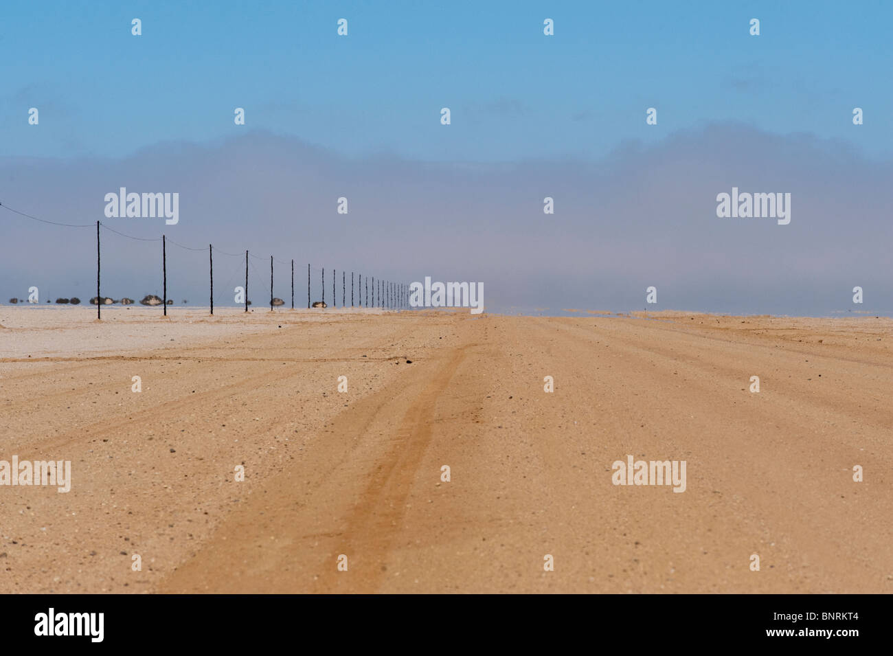 Road approaching the coast at Hentiesbaai the coast line is covered in fog Namibia Stockfoto