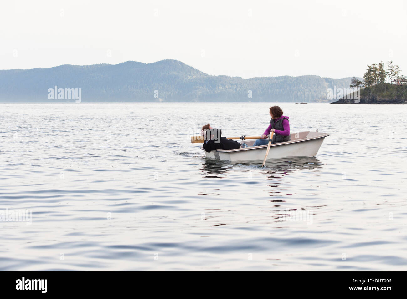 Ein junges Paar Zeile in den Puget Sound von Orcas Island in einem kleinen Ruderboot. Stockfoto