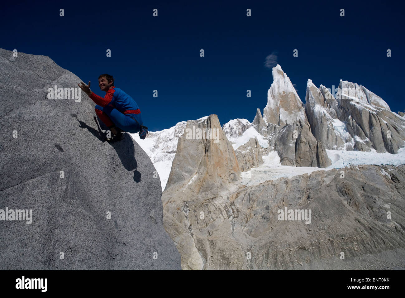 Mann im Anzug Spiderman klettert vor Berg. Stockfoto