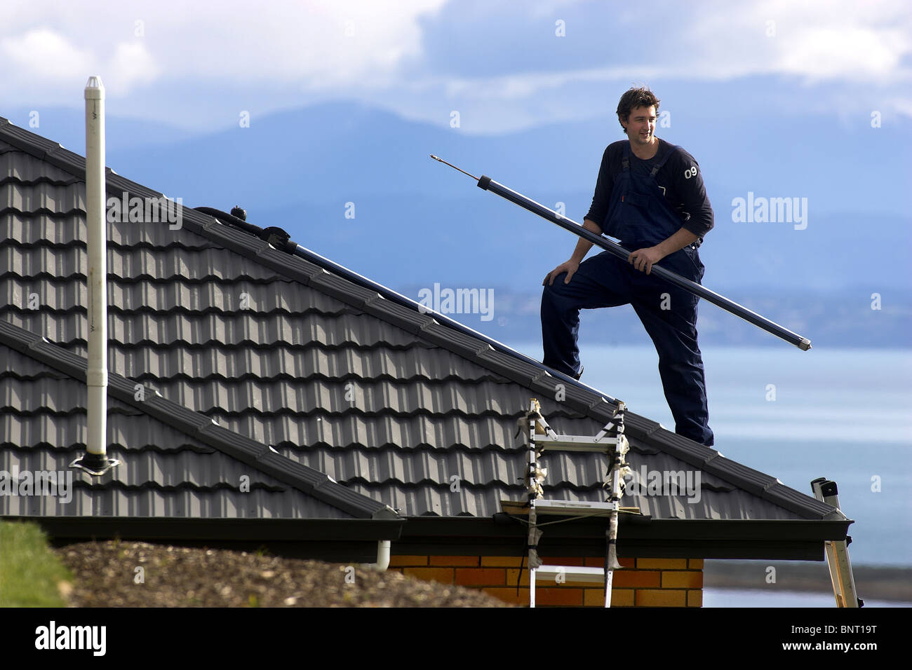 Qualifizierte Handwerker, die Installation von solar-Warmwasser-System zu einem Haus, Nelson, New Zealand, die Stadt mit der höchsten Sonnenscheinstunden Stockfoto