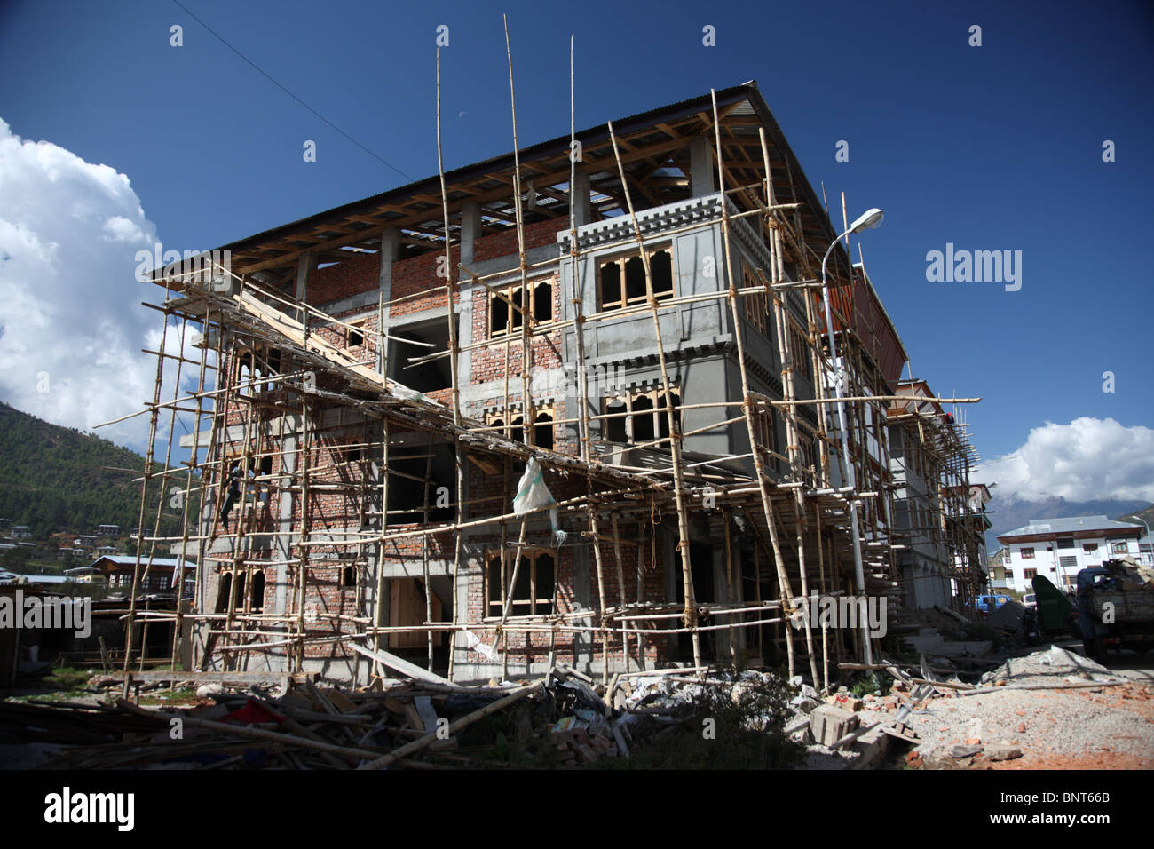 Ein großes Haus im Bau, umgeben von Bambus-Gerüst und Haufen von Steinen in Paro, Bhutan. Stockfoto