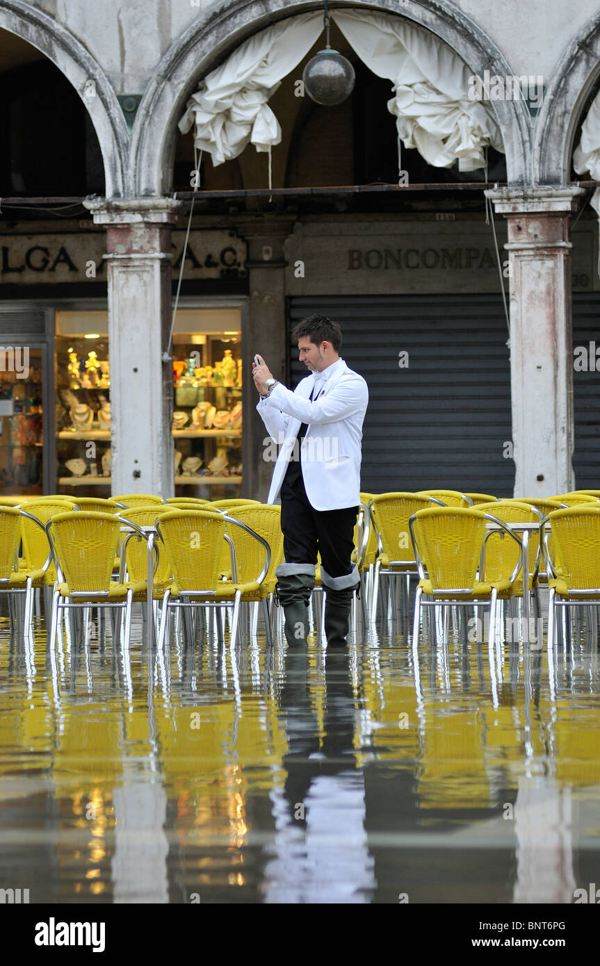Venedig. Italien. Ein Kellner fotografiert die steigende Flut am Markusplatz entfernt / Piazza San Marco. Stockfoto