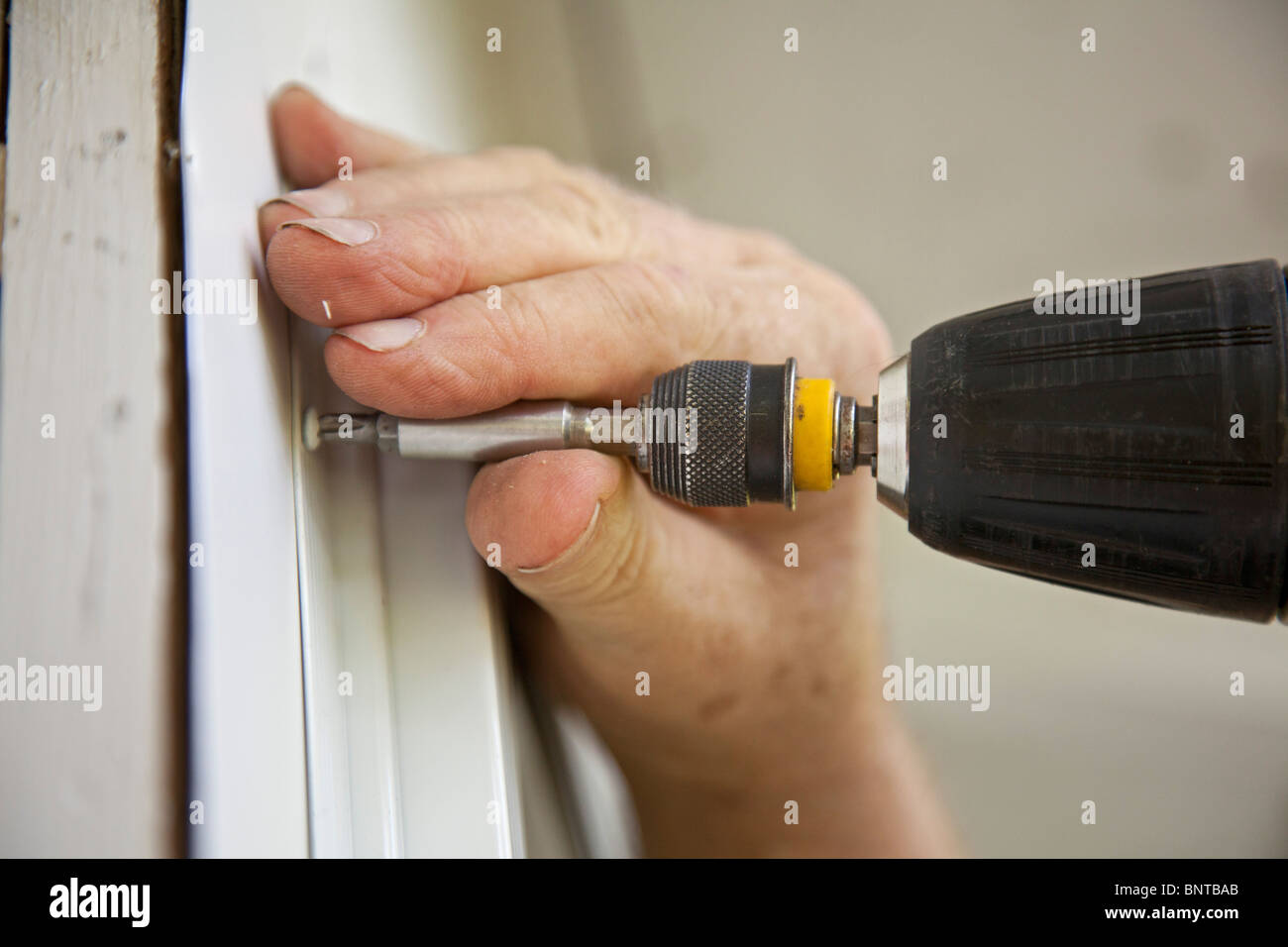 Prairieville, Michigan - ein Mann nutzt ein Akkuschrauber, um ein Fenster auf ein Landhaus zu installieren. Stockfoto