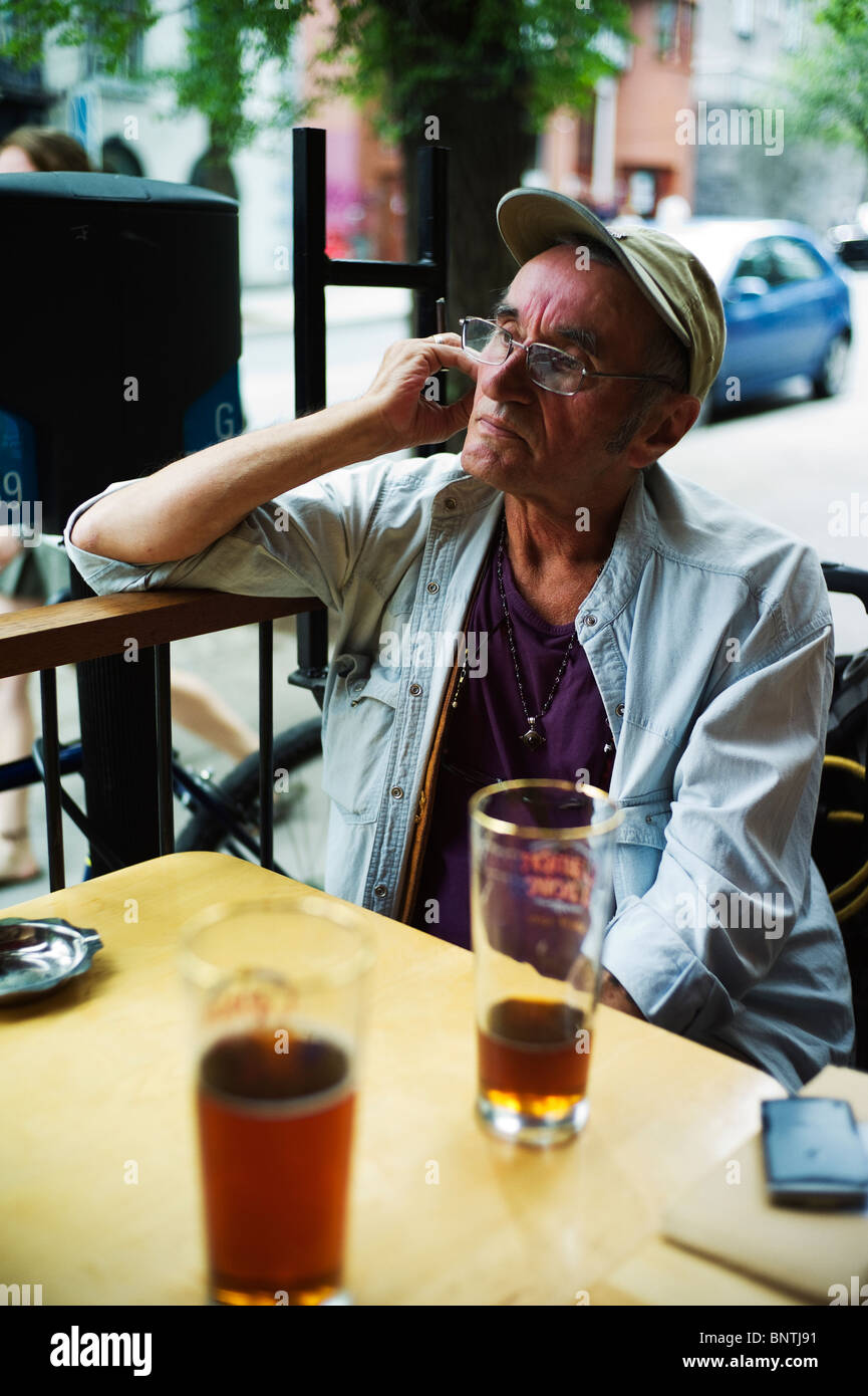 Alter Mann sieht vor der Kamera beim Sitzen am bar-Terrasse. Stockfoto