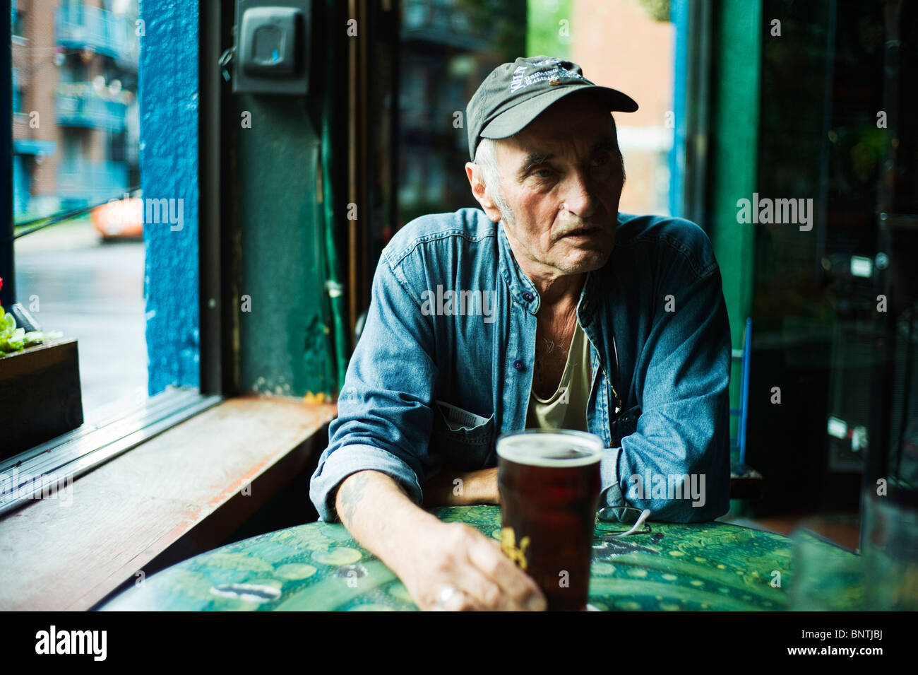 Alter Mann mit Pint Bier am Stehtisch. Stockfoto