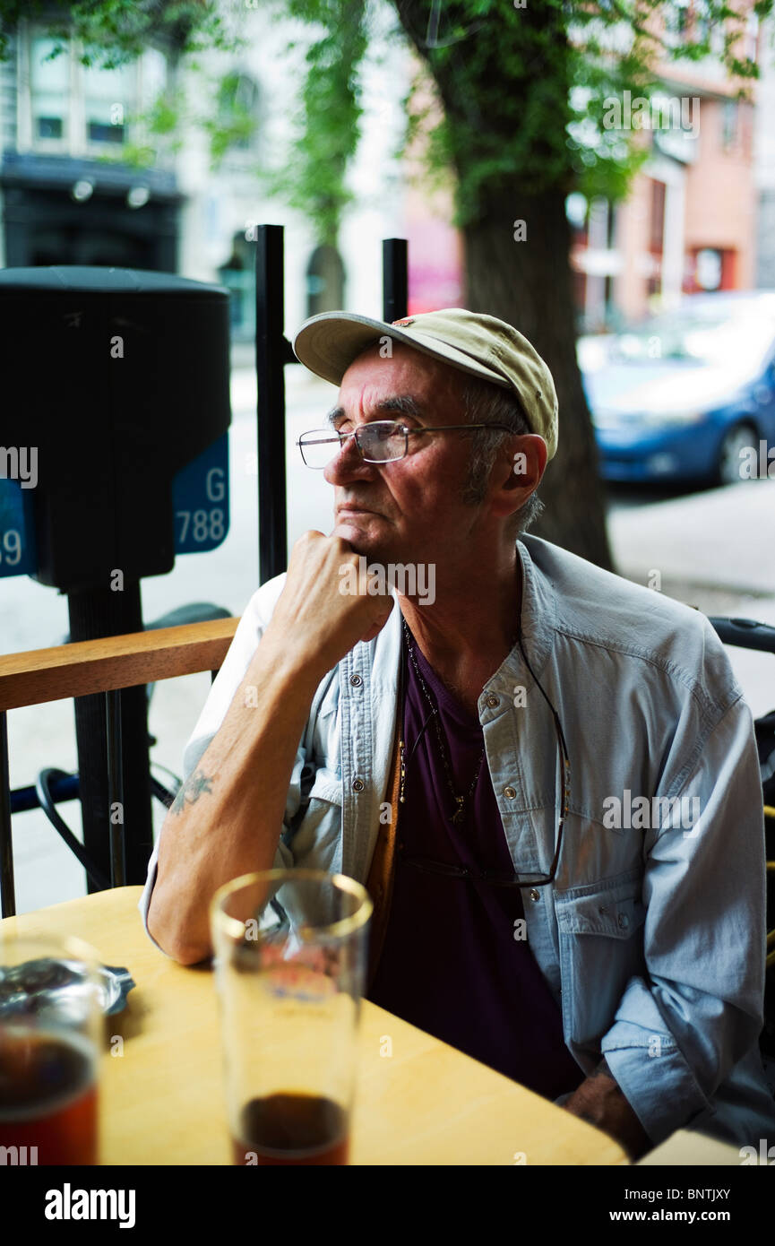 Alter Mann sieht vor der Kamera beim Sitzen am bar-Terrasse. Stockfoto