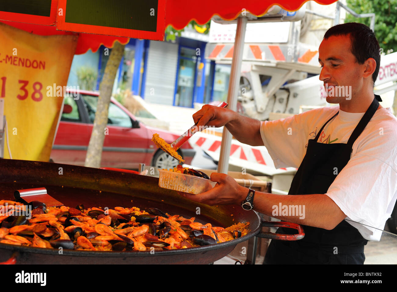 Mann Kochen Paella im Markt in der Bretagne, Frankreich. Stockfoto