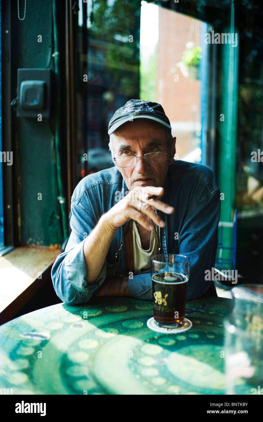 Alter Mann mit Zigarette am Tisch in der Bar. Stockfoto