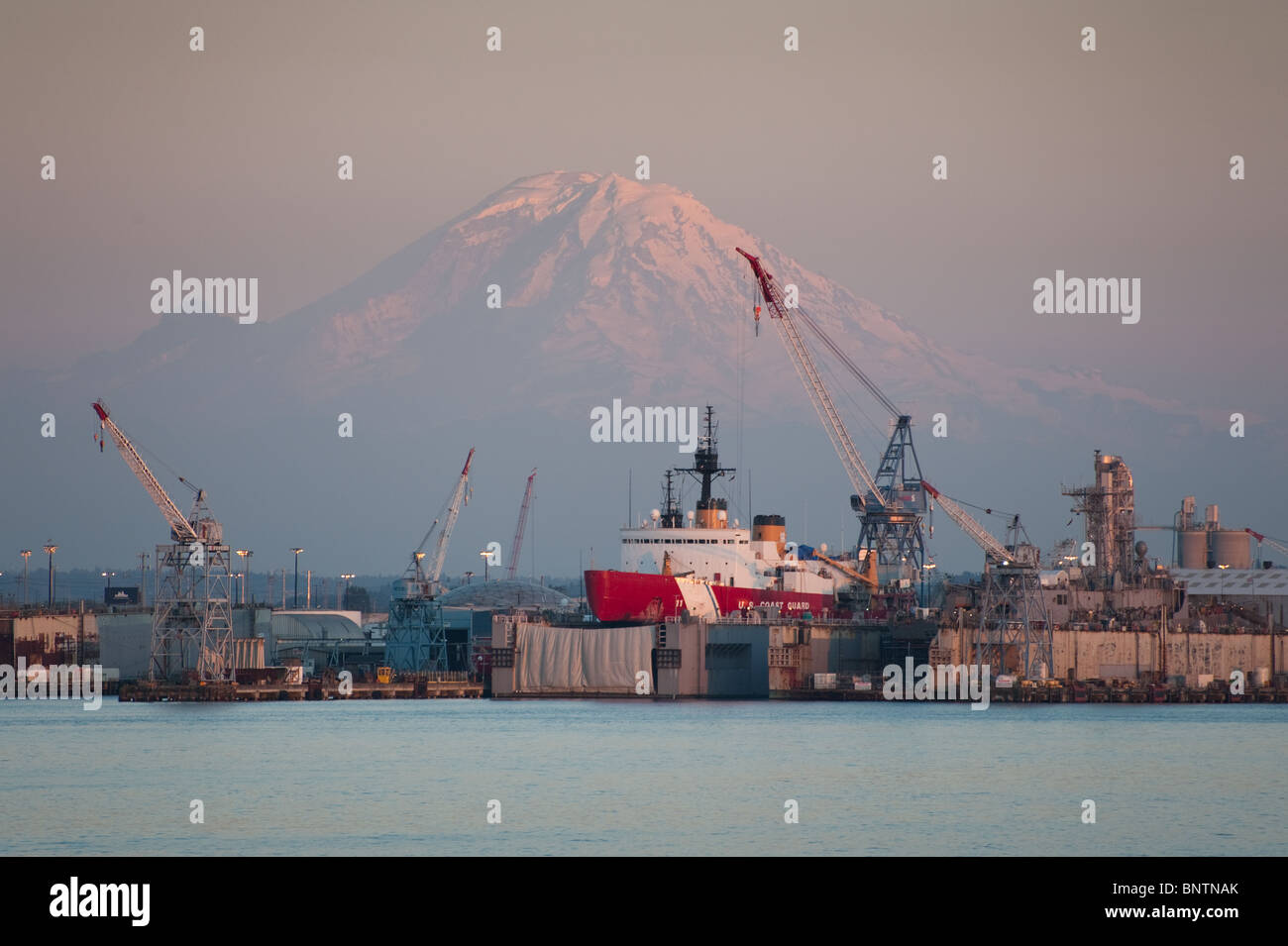 Riesige Kräne be- und Entladen der Fracht in den Hafen von Seattle, Washington, USA Schiffe ziehen im Trockendock für Reparaturen und Wartung. Stockfoto