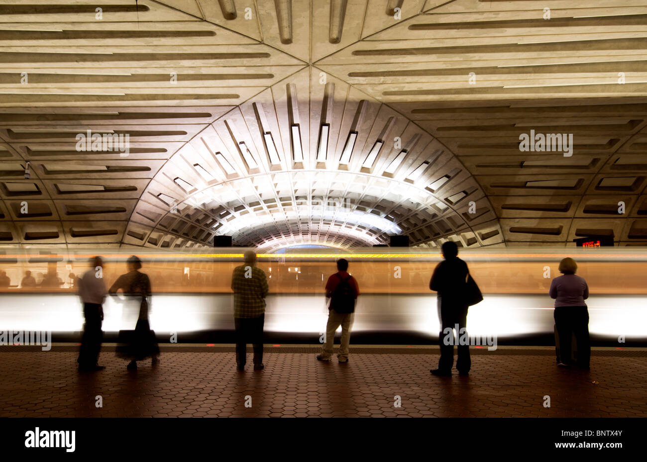 Pendler/Passagiere, die auf einem U-Bahnhofsplatz auf einen Zug warten, wenn ein Zug den Bahnhof in Washington DC, USA, verlässt Stockfoto