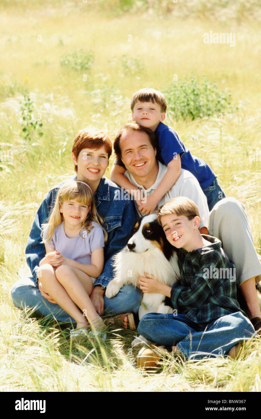 Familie und ihren Hund auf Wiese zusammensitzen Stockfoto