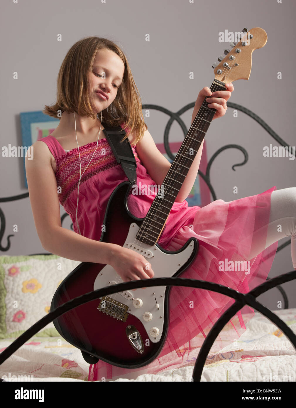 Junge Mädchen, die Gitarre zu spielen, auf ihrem Bett Stockfoto