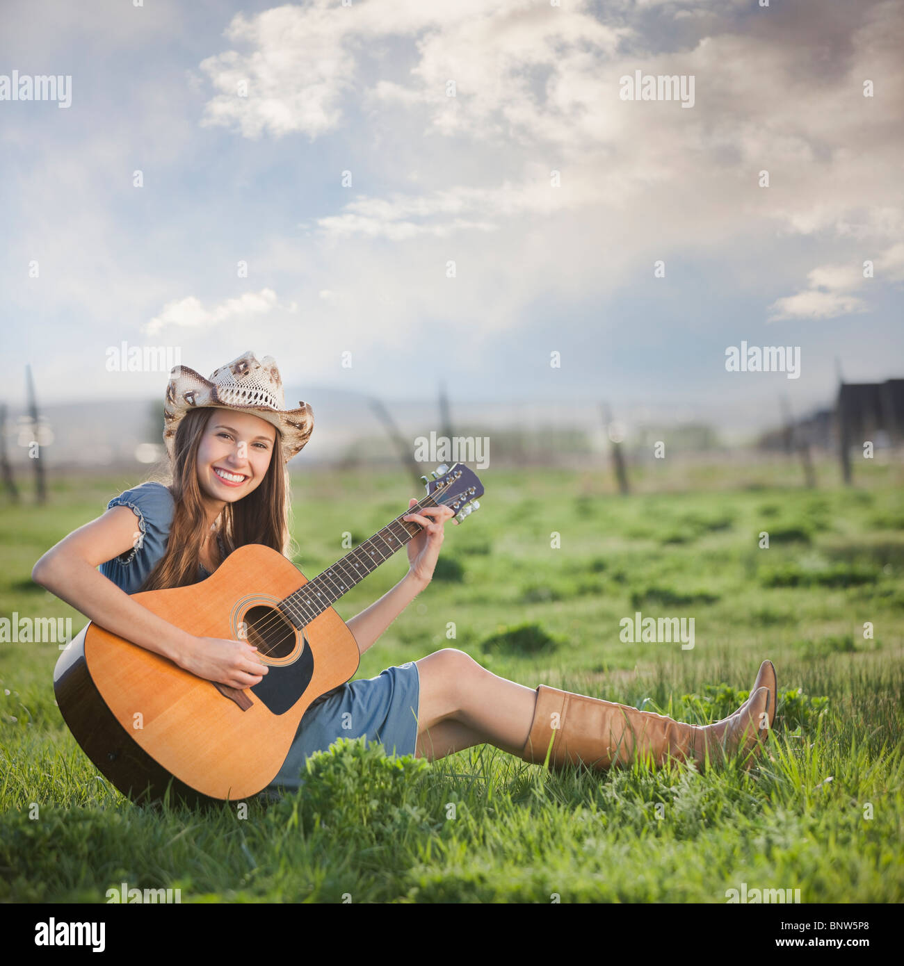 Cowgirl sitzen im Bereich Gitarre spielen Stockfoto