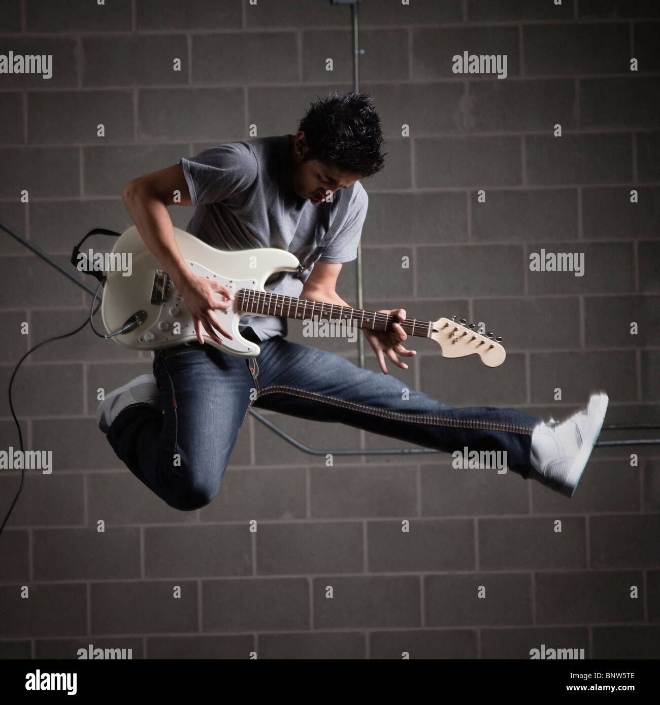 Mann springt in die Luft beim Gitarre spielen Stockfoto