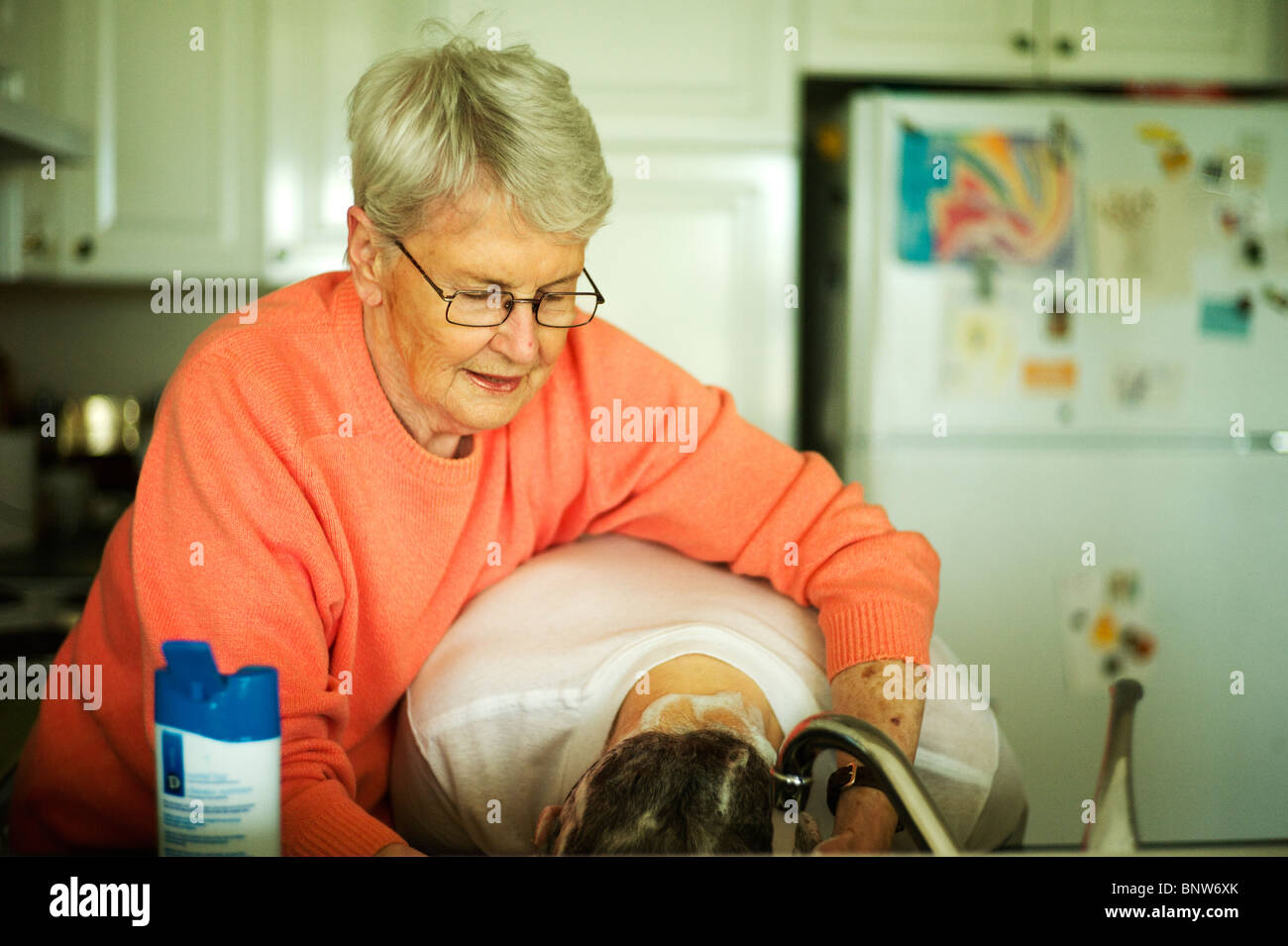 Alte Frau wäscht alten Mannes Haare im Spülbecken. Stockfoto
