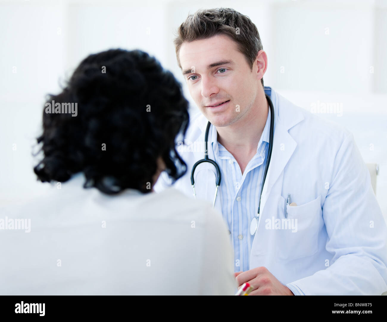 Hübscher Arzt im Gespräch mit seinem Patienten für den jährlichen Check-up Stockfoto