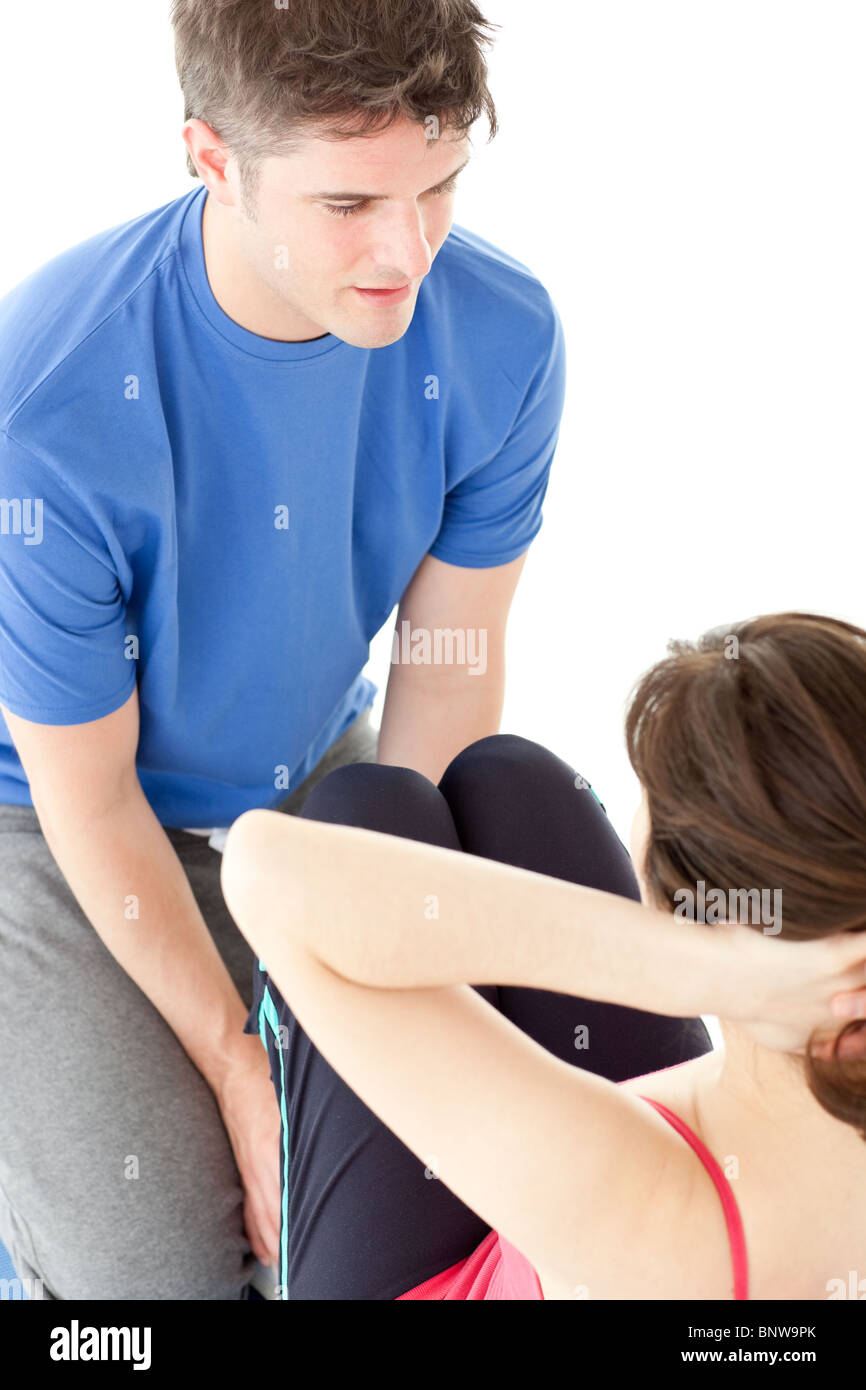 Junge Frau macht Sit-ups formten von ihrem personal trainer Stockfoto