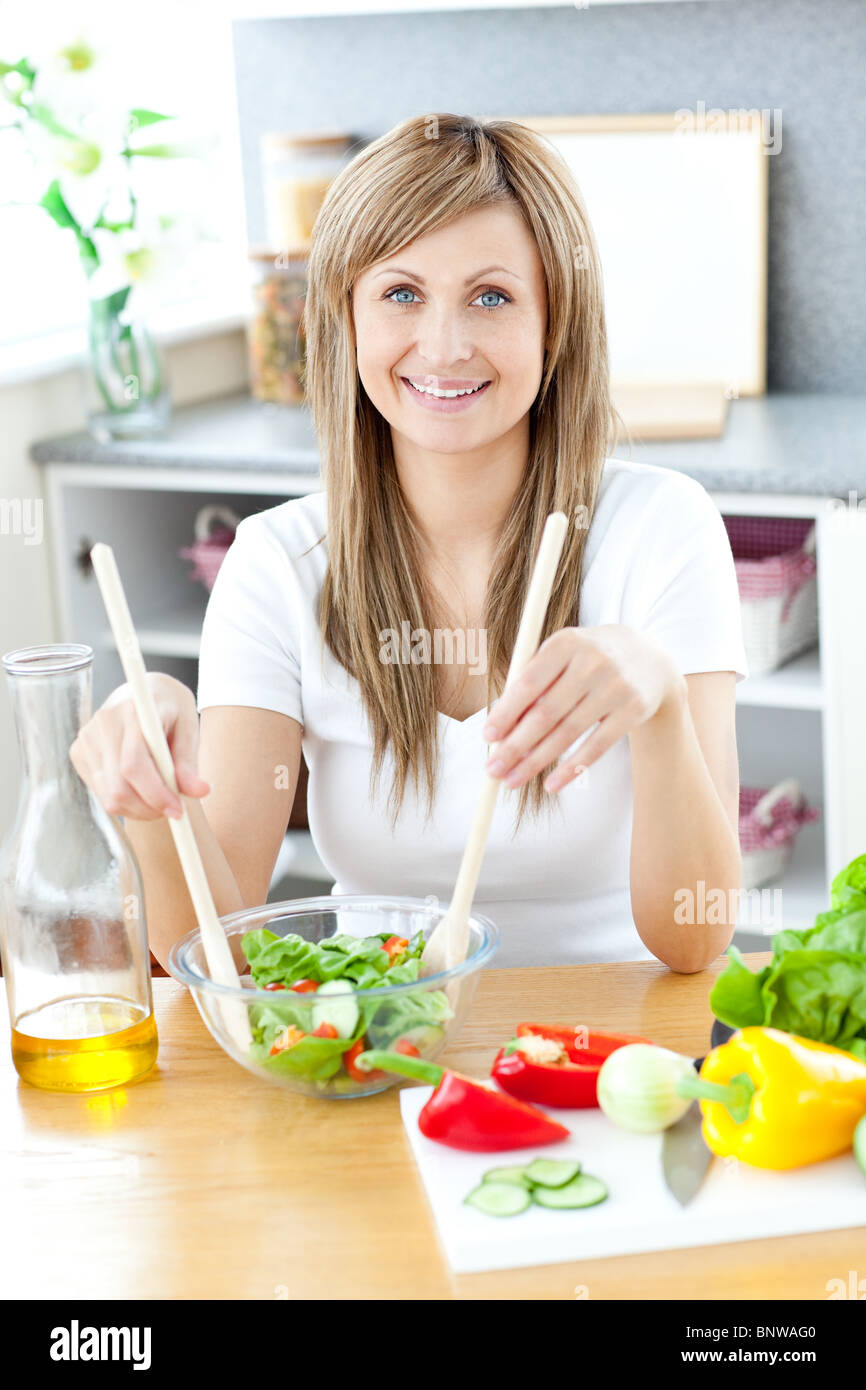 Nette Frau, die einen Salat in der Küche vorbereiten Stockfoto