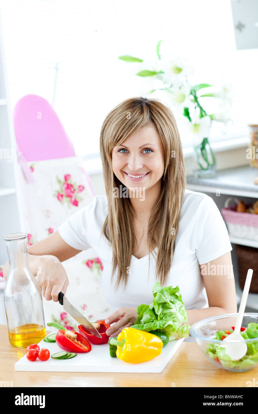 Junge Frau, die einen Salat in der Küche vorbereiten Stockfoto