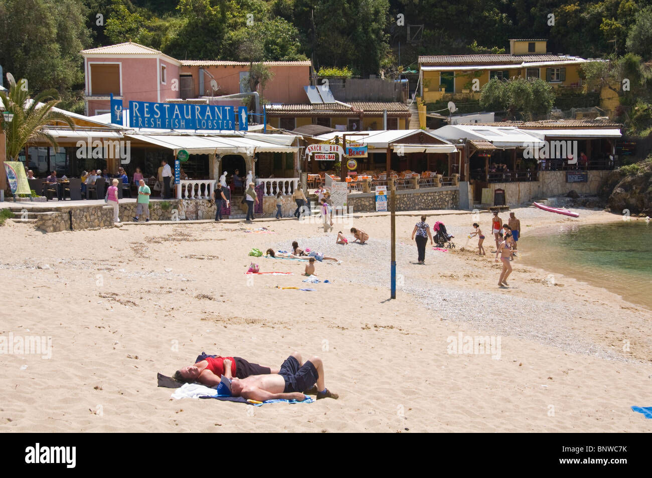 Corfu Beach. Touristen, die auf sandigen Strand bei Paleokastritsa auf der griechischen Insel Korfu Griechenland GR entspannend Stockfoto