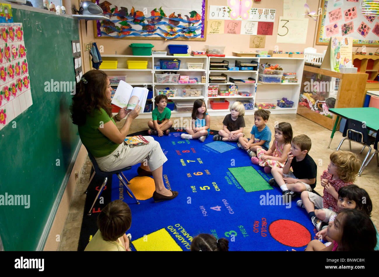 Spanisch Lehrerin liest Buch auf Spanisch zur Gruppe der multi-ethnischen Vorkindergarten-Alter Kinder im zweisprachigen Kindergarten Stockfoto