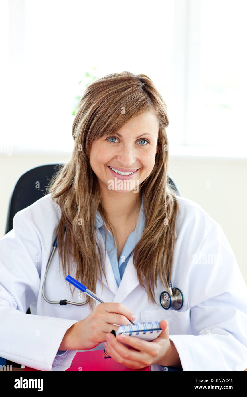 Lächelnde Ärztin schreiben ihre Diagnose Stockfoto