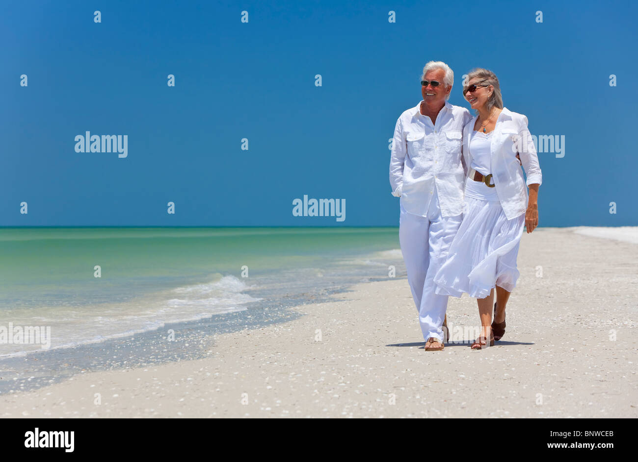 Romantische senior Mann und Frau Brautpaar zu Fuß auf einem einsamen tropischen Strand mit hellen klaren blauen Himmel Stockfoto