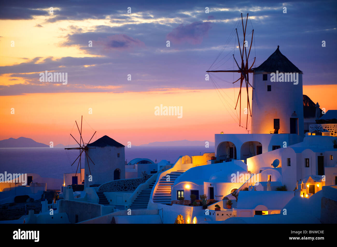 Oia (Ia) Santorini Windmühlen und Stadt bei Sonnenuntergang, Thira Island, griechische Kykladen-Inseln Stockfoto