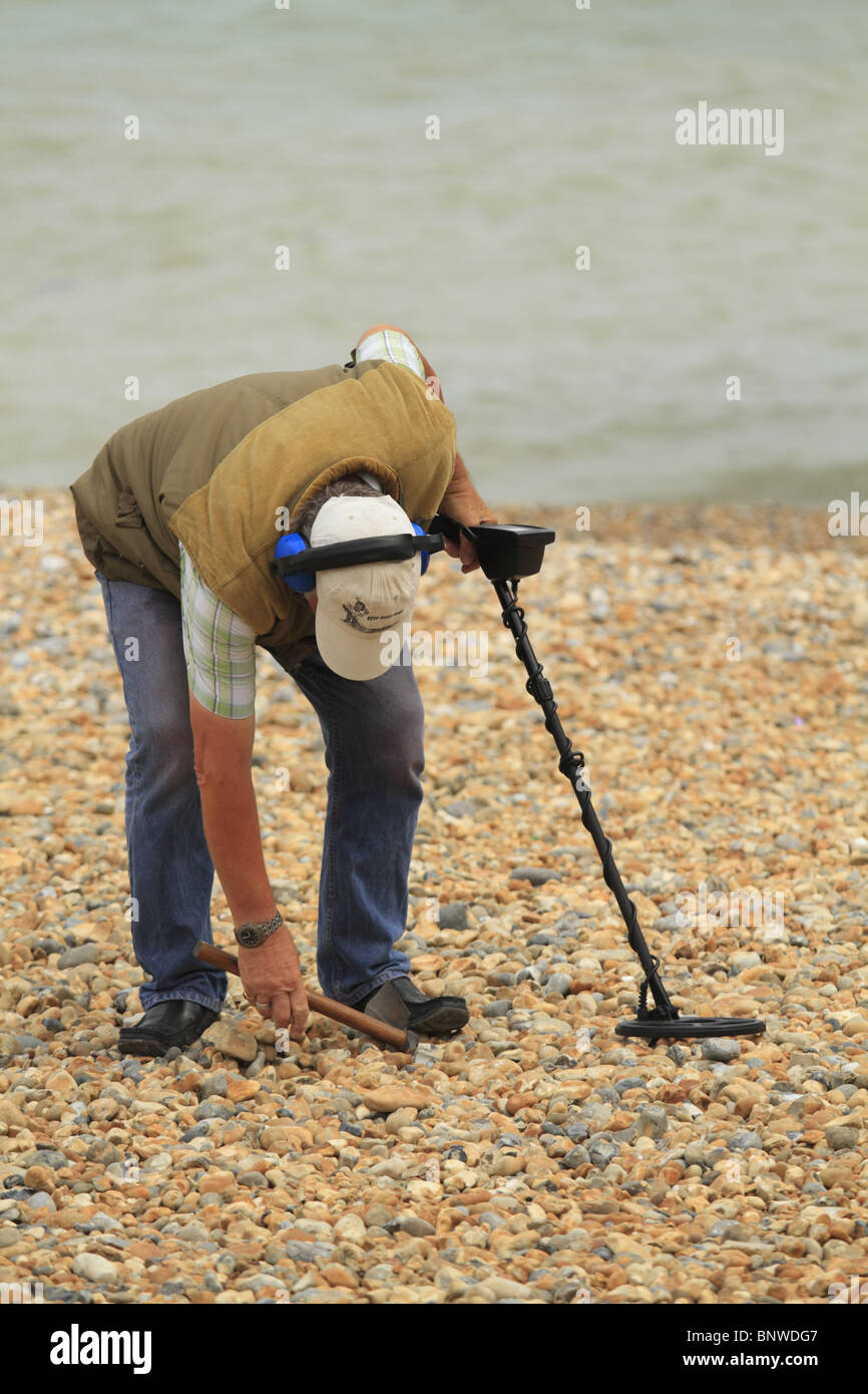 Ein Mann sucht nach vergrabenen Schatz mit einem Metalldetektor auf Eastbourne Strand, East Sussex, England Stockfoto