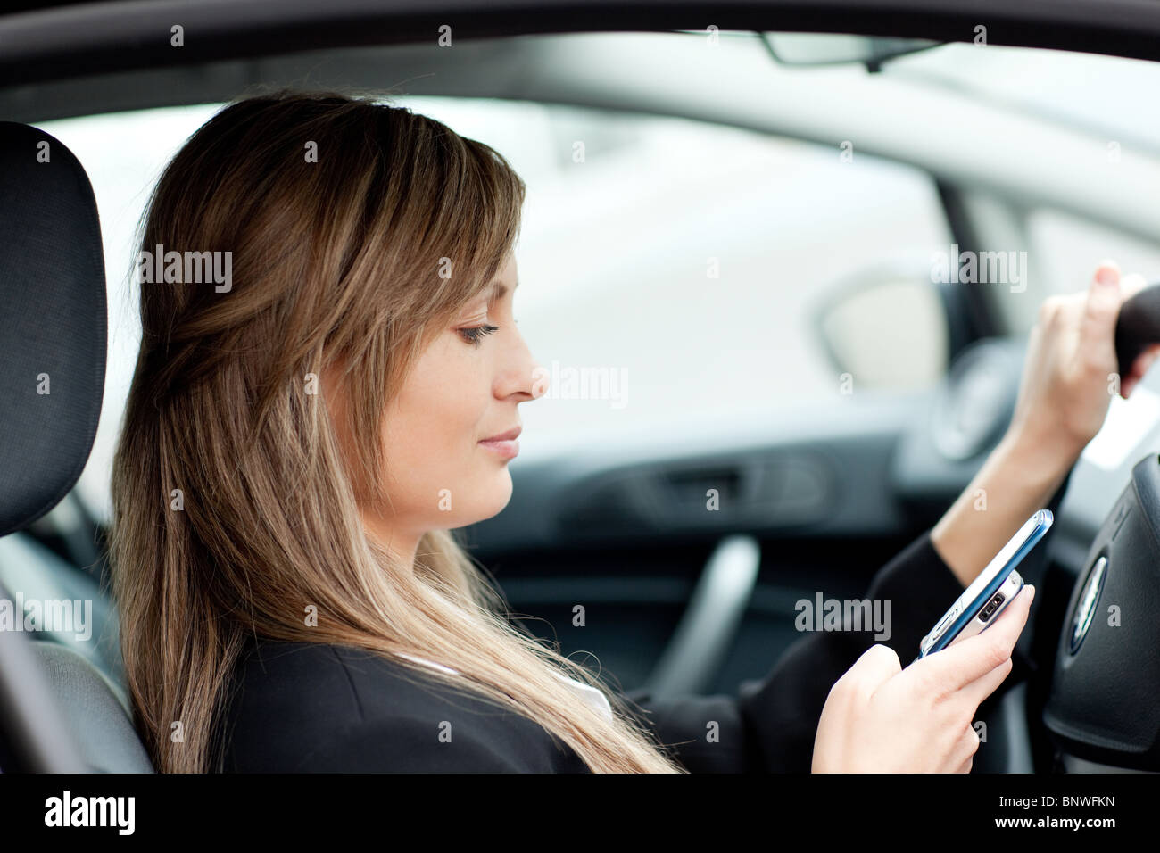 Schöne Geschäftsfrau SMS während der Fahrt Stockfoto